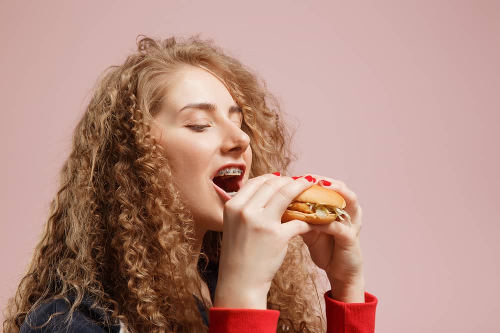 young girl eating a sandwich while wearing braces